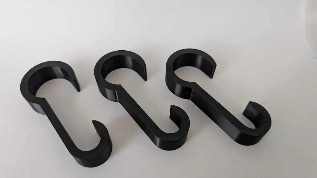 Perspektivische Ansicht von drei schwarzen Reling-Clips aus Kunststoff auf weißem Untergrund. Die robuste Bauform der Haken ist für den Einsatz im Wassersport zur Kabelführung optimiert.